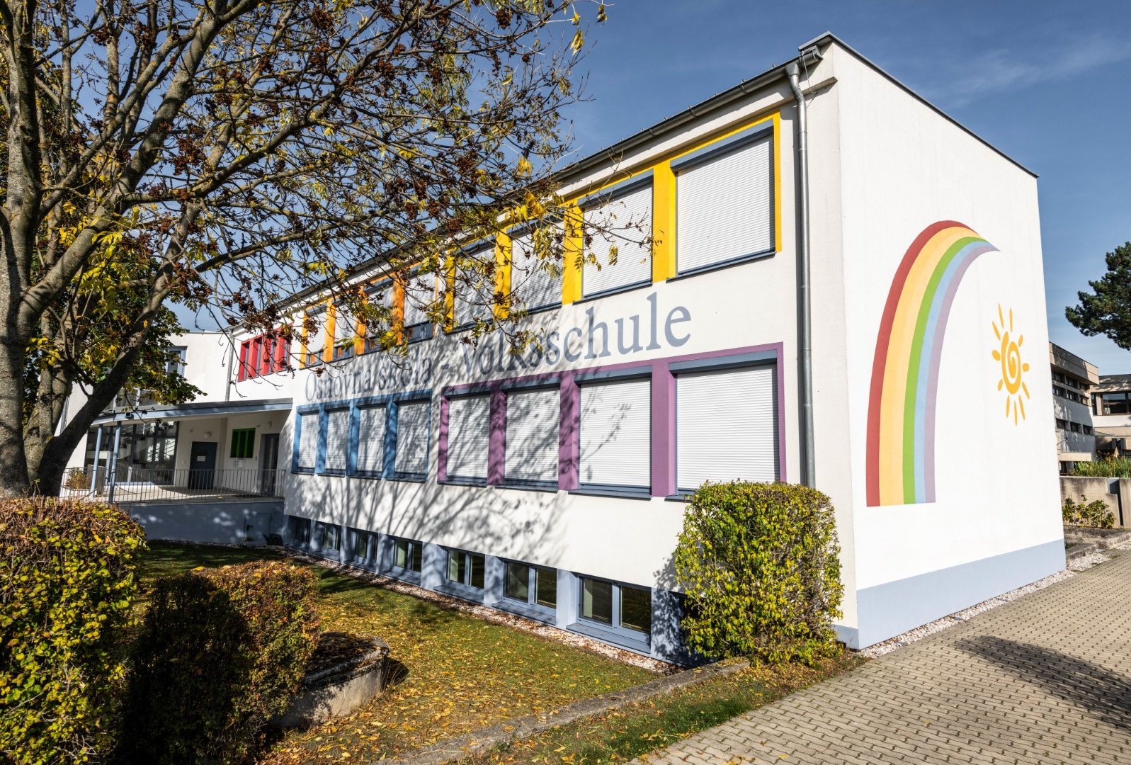 ein Regenbogen ziert die seitliche Mauer der Volksschule